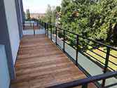 Balkon mit Stahltragwerken, Holzbohlen und Geländern mit Glasfüllung
