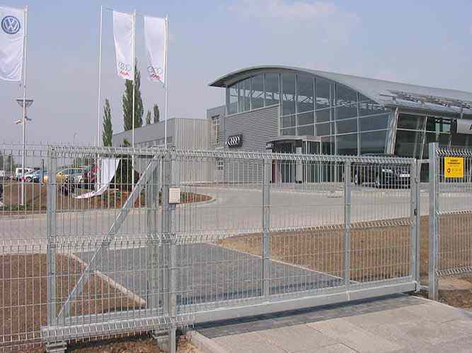 Freitragendes Schiebetor und Zaunfelder mit Gitterfüllung aus verzinktem Stahl. Eingebaut Rollenmechanismus mit Kunststoffrollen und Schiebetorprofil mit Führungsstegen