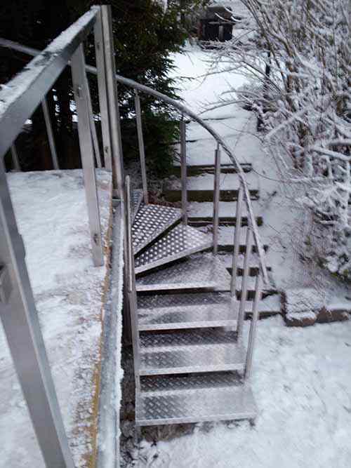 Wendeltreppe aus Edelstahl mit Stufen aus Alublech. Edelstahl -Handlauf und –Pfosten aus Vierkantrohr