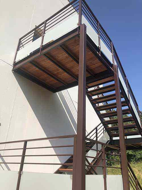 Stahlprofiltreppe, Holzbohlen und Geländer mit Glasfüllung.